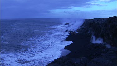 Waves crashing on black solidified lava beach.