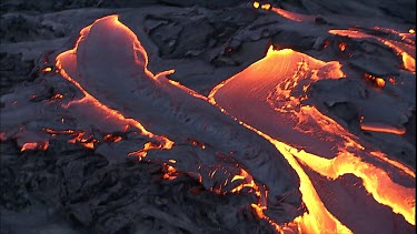 Steam and lava flow. Recently solidified lava crust. Tilt down along lava flowing over crust.