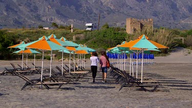 Tourists Walk Between Orange & Green Parasols, Frangokastello, Crete, Greece