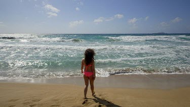 Teenage Girl Walks In & Out Of Sea In Pink Bikini, Falasarna, Crete, Greece