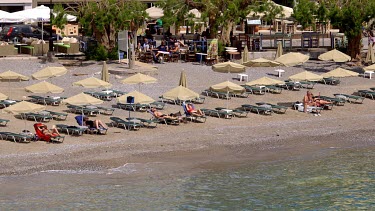 Tourists Sunbathing On Beach, Agios Nikolaos, Crete, Greece