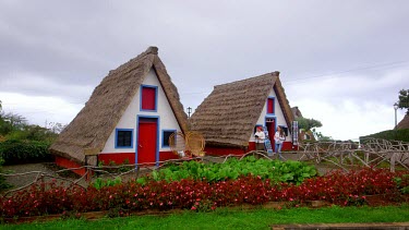 Local Lady & Tourist At Traditional Thatched Triangular Houses, Santana, Madeira, Portugal